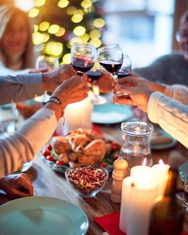Friends toasting wine glasses at a candlelit holiday dinner