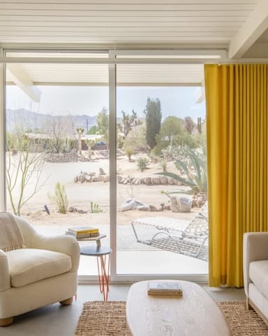 Bright living room with yellow curtains open to the desert garden